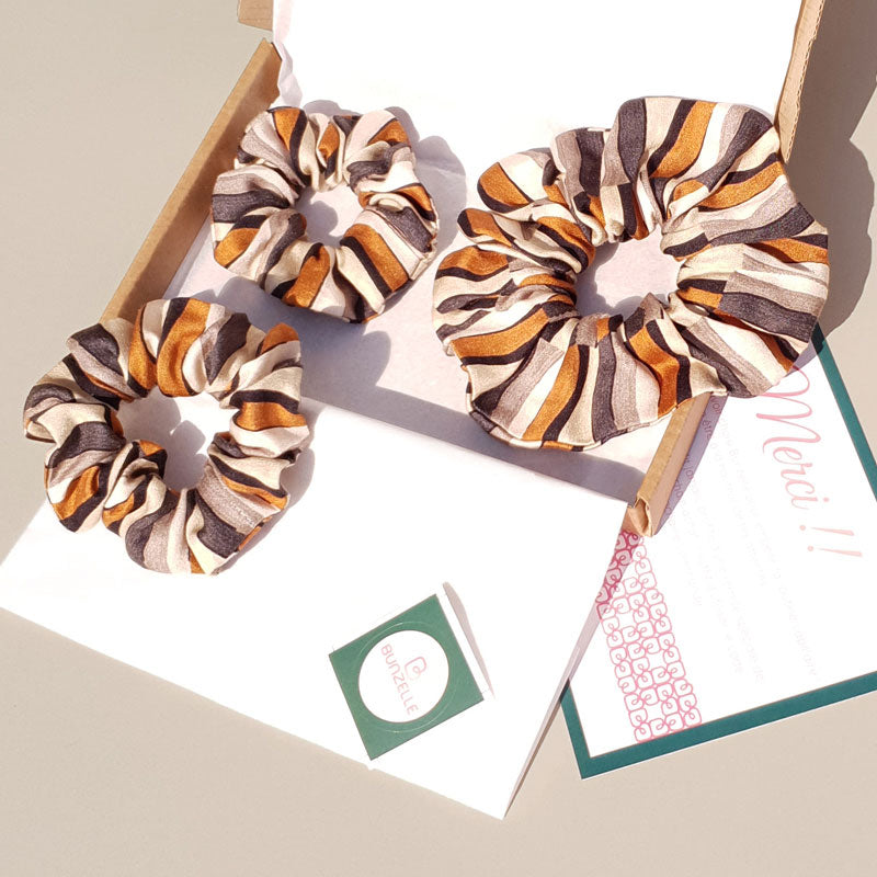 Ensemble de 3 chouchous cheveux aux couleurs orange et gris évoquant les safaris dans leur packaging Bunzelle