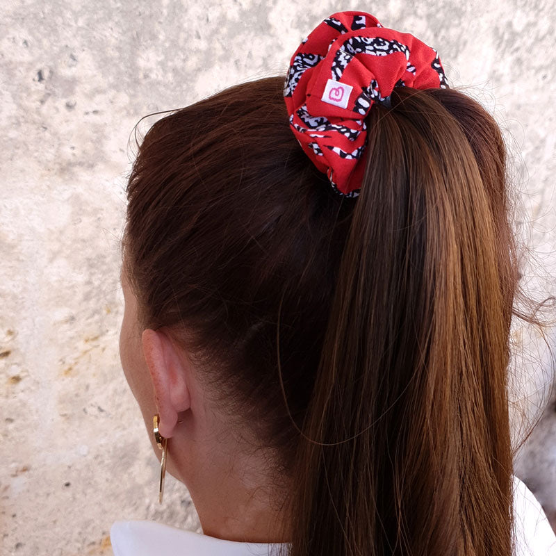 une femme a les cheveux attachés en queue de cheval avec un chouchou rouge à zébrures Bunzelle de taille médium