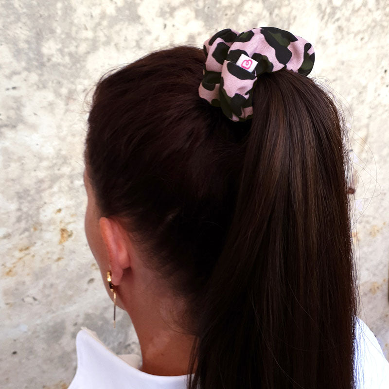 une femme a les cheveux attachés en queue de cheval avec un chouchou rose poudré à motif léopard Bunzelle de taille médium