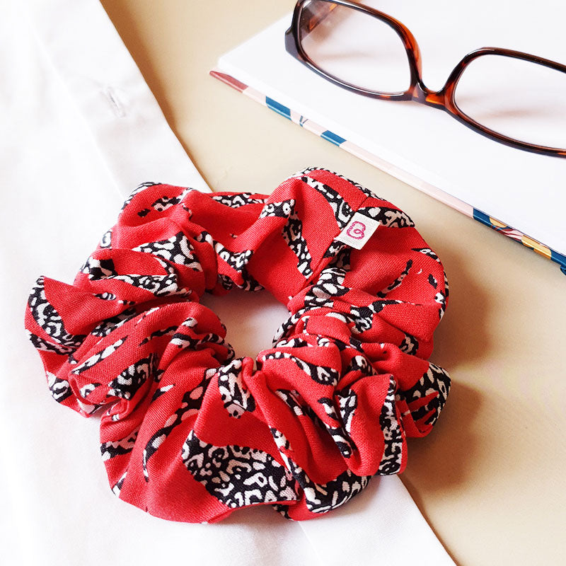 Un maxi chouchou rouge, zèbre rouge de Bunzelle, est posé à côté d'une paire de lunettes