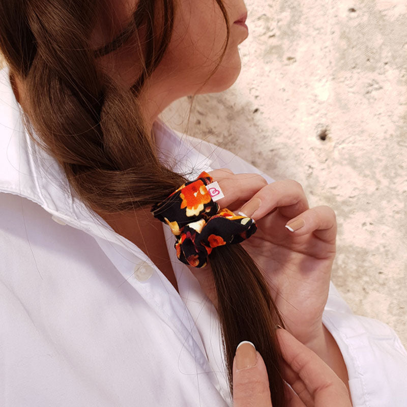 une femme a attaché sa tresse avec un mini chouchou noir à fleurs colorées Bouquet vintage de Bunzelle